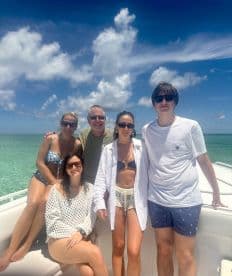 A cheerful group poses on the deck of a boat under a bright sky, capturing a memorable moment on the water — perfect for family outings or friends' adventures.