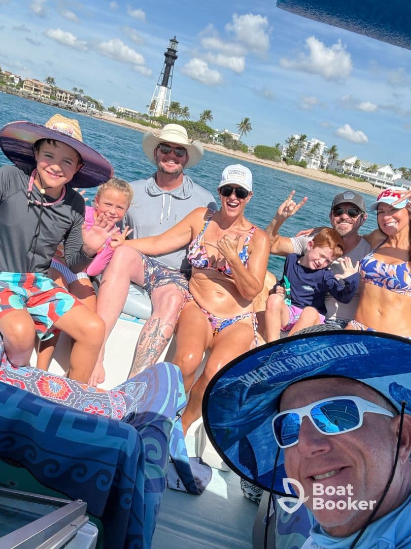 A joyful group of family and friends poses for a fun photo on a boat, with a lighthouse in the background — capturing the essence of a memorable day on the water.
