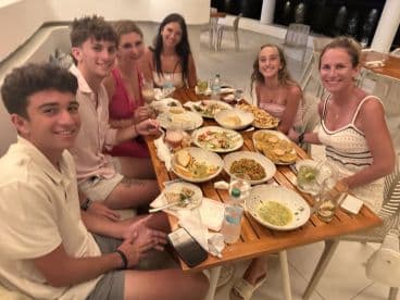 A lively group enjoys a festive dinner together, featuring a variety of delicious dishes and cocktails, perfect for celebrating special moments on vacation.