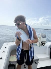 A young man kisses his catch of the day, showcasing a successful fishing trip on the water. This moment captures the thrill of fishing and the joy of outdoor adventures.