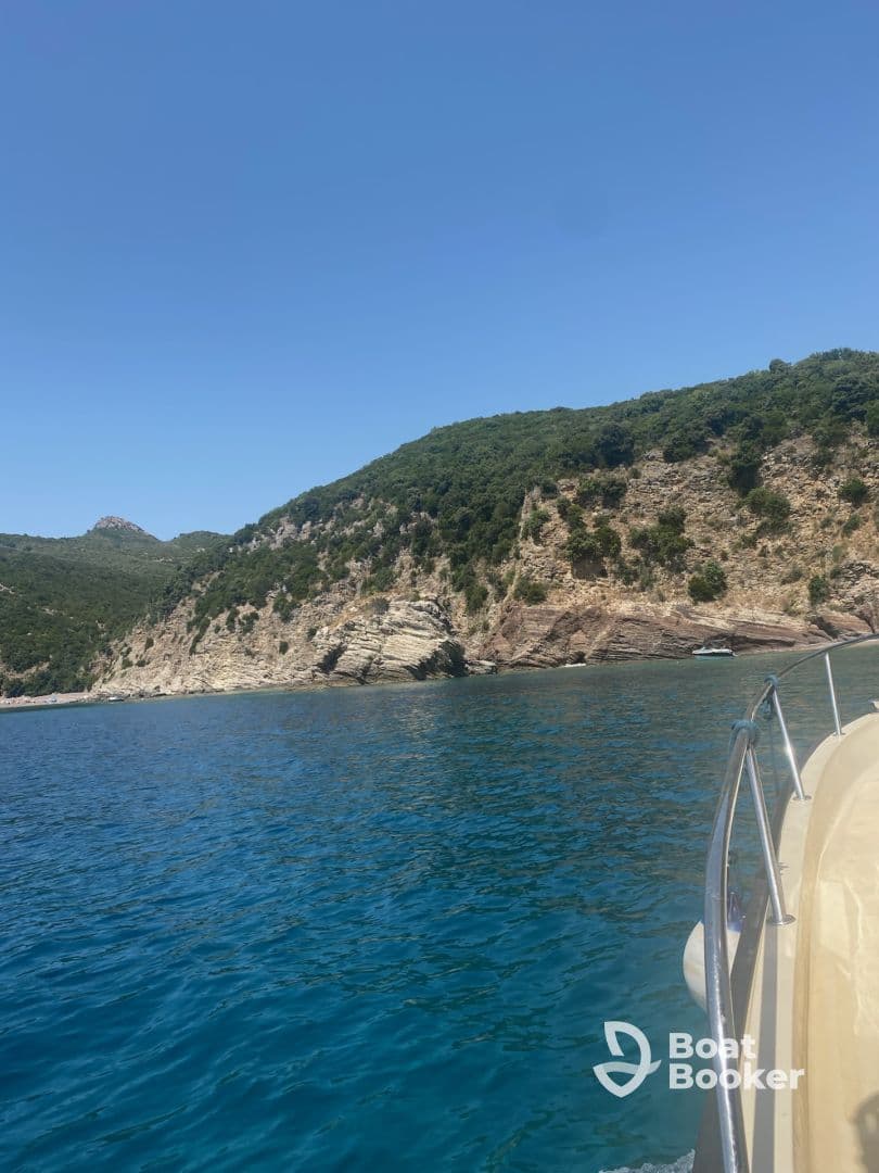 A scenic view of a boat navigating along a stunning coastline, showcasing the beautiful blue waters and lush greenery of the surrounding landscape.