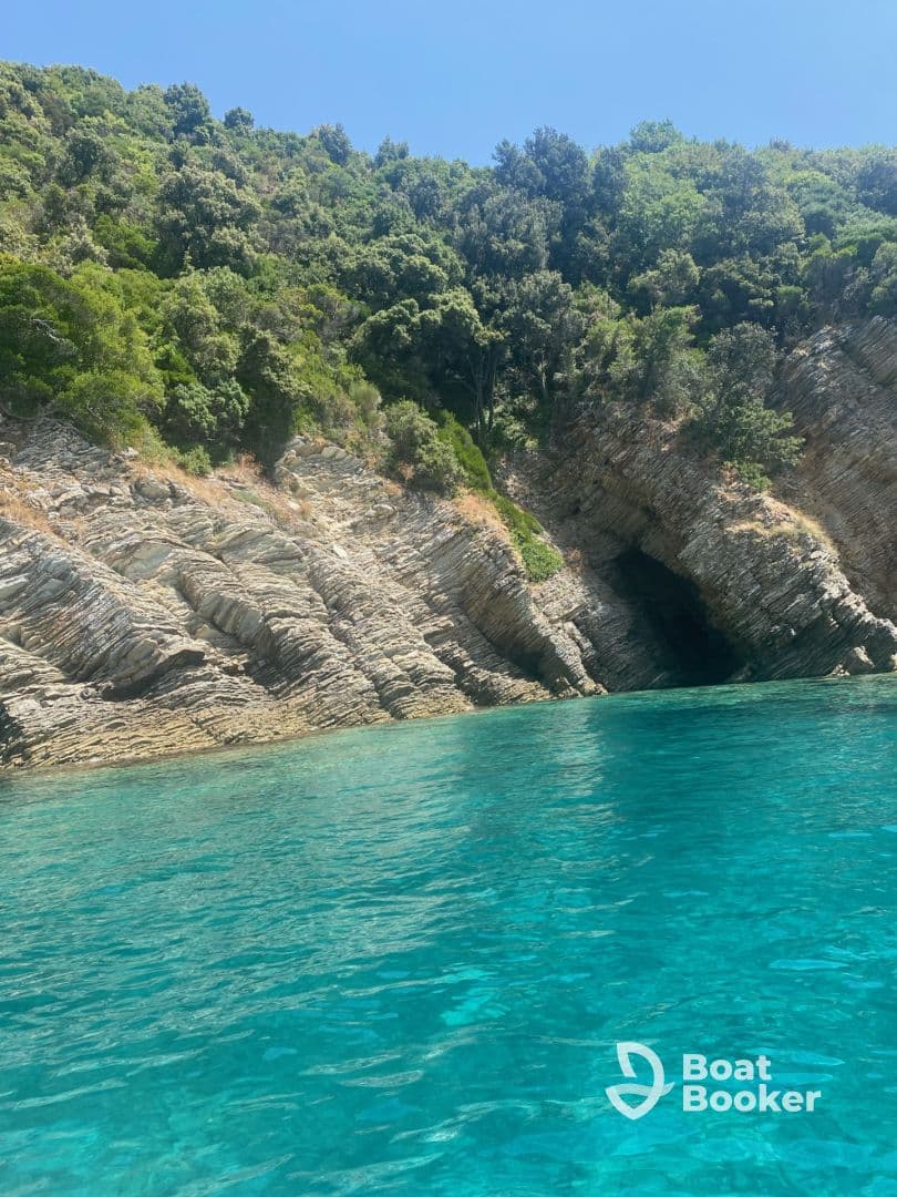 A stunning view of a rocky coastline with a cave, surrounded by crystal-clear turquoise waters — a perfect destination for boating adventures and exploration.