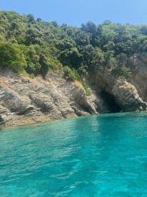 A stunning view of a rocky coastline with a cave, surrounded by crystal-clear turquoise waters — a perfect destination for boating adventures and exploration.