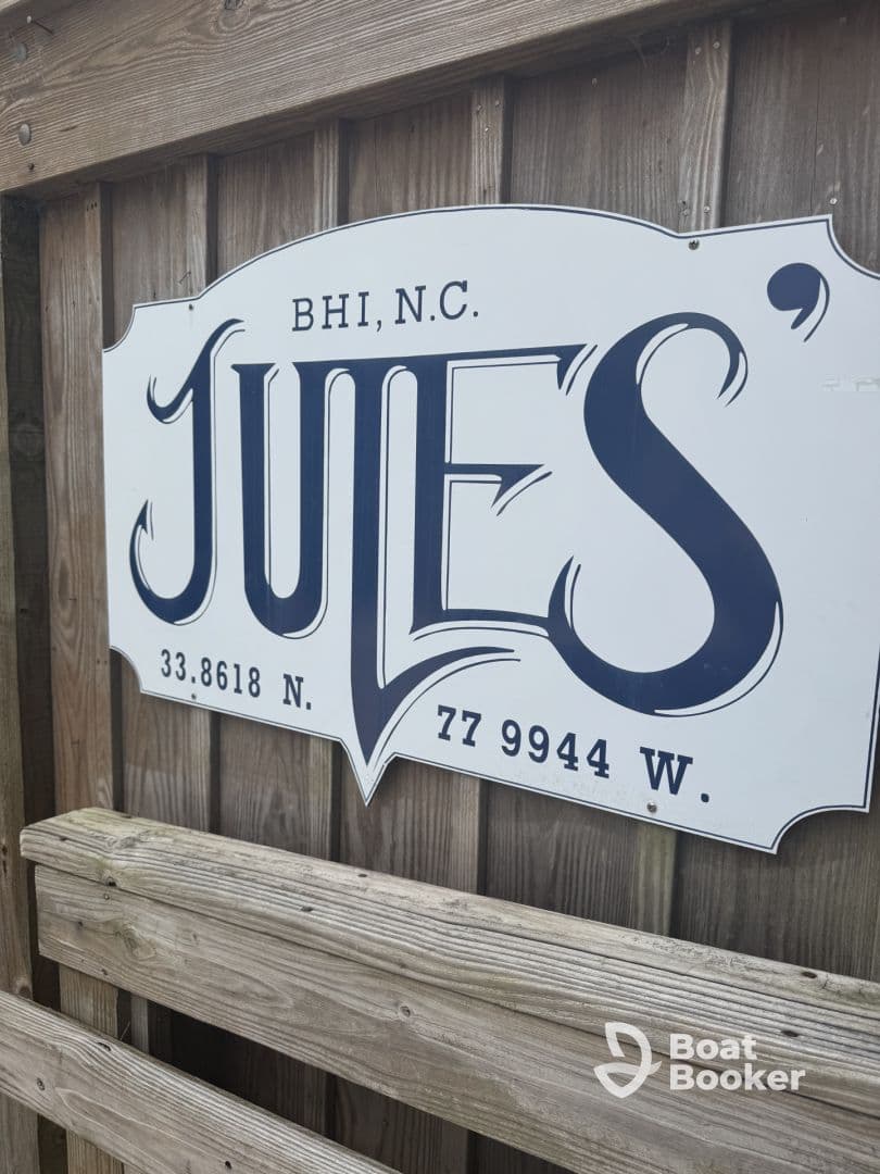 A close-up of a sign for 'Jules' located in BHI, N.C., featuring geographical coordinates. Ideal for identifying local attractions.