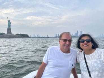 A couple enjoys a scenic boat tour with the Statue of Liberty in the background, capturing the essence of New York City’s iconic skyline.