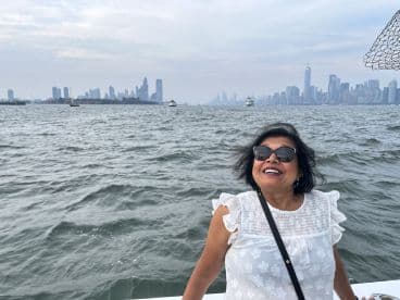 A joyful woman enjoys a boat ride with a stunning city skyline in the background, capturing the essence of a perfect day on the water.
