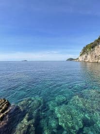 A stunning view of crystal-clear waters and a rocky coastline, showcasing the natural beauty of the area — perfect for exploring and relaxing on a boat trip.