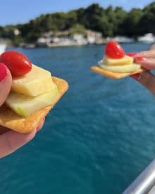 Delicious snacks featuring cheese, cucumber, and cherry tomatoes are enjoyed on a boat, perfect for a relaxing day on the water.