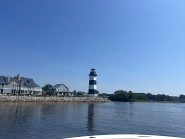 A picturesque view of a striking black and white lighthouse alongside charming waterfront homes, capturing the essence of coastal beauty.