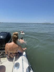 A group enjoys a fun day on the water, with one person swimming and others relaxing on the boat — perfect for summer adventures and water activities.