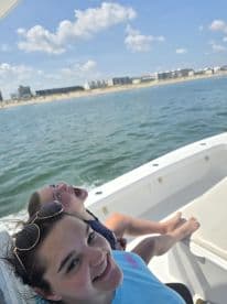 Two young girls enjoy a sunny day on a boat, smiling and having fun as they cruise along the beach — a perfect snapshot of summer adventures on the water.