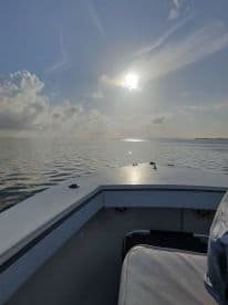 A serene view from the front of a boat, capturing the sun reflecting on calm waters — perfect for peaceful outings and sunset cruises.