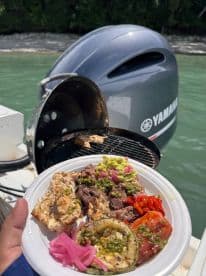 A delicious spread of grilled meats and vegetables prepared on a boat's BBQ grill, perfect for onboard dining and catering experiences.