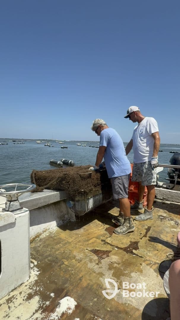 Two crew members work on a fishing boat, preparing equipment while surrounded by a scenic ocean view — a glimpse into the fishing experience on the water.