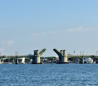 A scenic view of a drawbridge opening over a waterway, showcasing the infrastructure that facilitates boat passage.