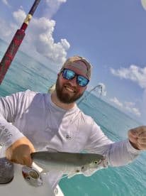 A happy angler proudly displays his catch while fishing in the clear blue ocean, showcasing the thrill of a successful day on the water.