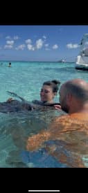 A couple interacts with a friendly stingray in crystal-clear waters, showcasing a memorable wildlife experience in a tropical paradise.