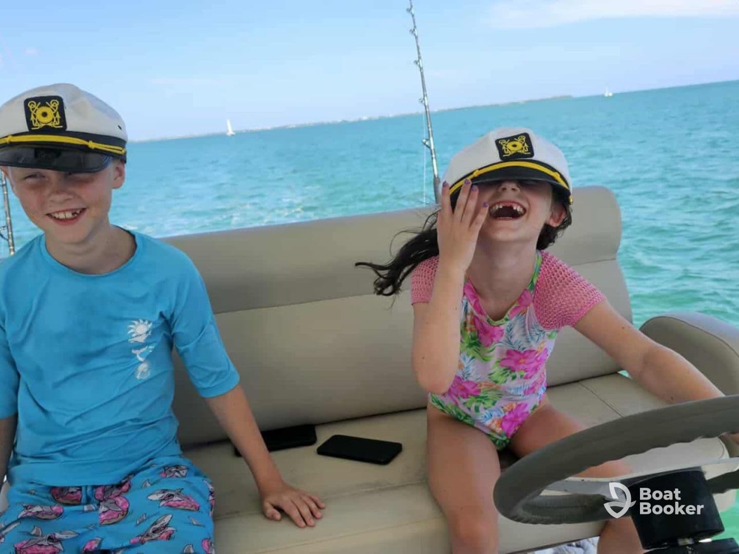 Two children wearing captain hats enjoy a fun moment on a boat, showcasing the joy of a family outing on the water.