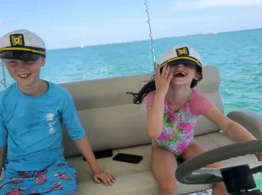 Two children wearing captain hats enjoy a fun moment on a boat, showcasing the joy of a family outing on the water.