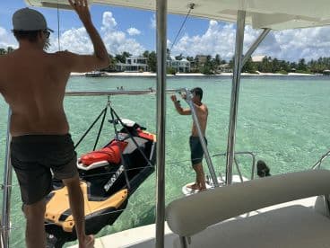 Guests enjoy a sunny day on the water, with a jet ski ready for adventure and a child swimming nearby — perfect for family fun in the clear turquoise waters.