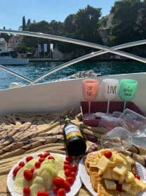 A beautifully arranged spread of fresh cucumbers, cherry tomatoes, and cheese crackers alongside a bottle of Chardonnay, perfect for a relaxing day on the water.