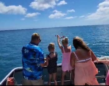 A joyful family celebrates on a boat, with children throwing flowers into the ocean — a memorable moment on the water.
