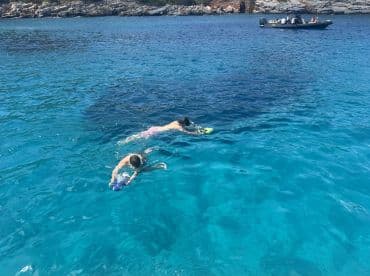 Two children enjoy snorkeling in crystal-clear waters, showcasing a fun and adventurous day on the water.
