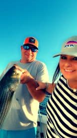 A joyful couple proudly displays their catch while fishing on the water, capturing a memorable moment of celebration and adventure.