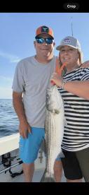 A couple proudly displays their catch of a striped bass while enjoying a day of fishing on the water — a perfect moment for fishing enthusiasts.