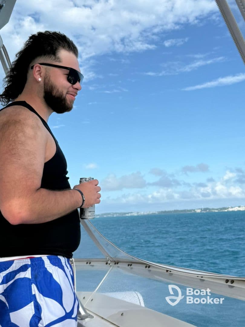 A man enjoys the scenic view from the deck of a boat, holding a drink and soaking in the beautiful ocean surroundings — perfect for a relaxing day on the water.