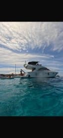 A lively scene featuring guests enjoying the turquoise waters next to a boat, perfect for summer adventures and water activities.