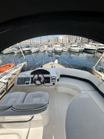 A well-appointed helm area inside a boat, featuring comfortable seating and modern controls, perfect for navigating the waters.