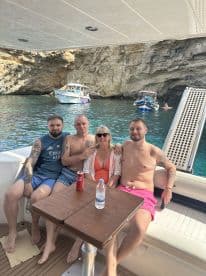 A cheerful group enjoys a sunny day on a boat, capturing a moment of fun and relaxation amidst beautiful scenery.