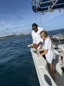 A young girl learns to fish with guidance on a boat, capturing a memorable moment of fun and education on the water.