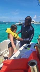 An adult assists a child in putting on a life jacket on a boat, ensuring safety for a fun day on the water. Perfect for family boating adventures.