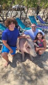 A memorable moment with children interacting with a friendly pig on the beach, showcasing a unique wildlife experience in a tropical setting.