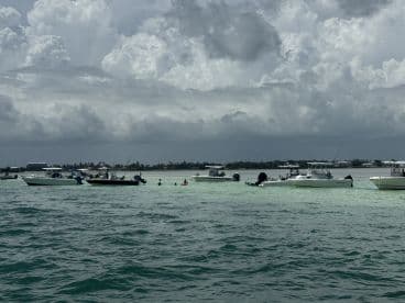 A lively scene at a sandbar with multiple boats and people enjoying the water, perfect for a fun day out on the water.