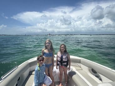 Three children enjoy a sunny day on a pontoon boat, showcasing the fun of summer boating adventures.