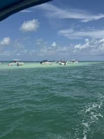 A vibrant scene at a sandbar with multiple boats anchored, showcasing a lively atmosphere perfect for swimming and socializing on the water.