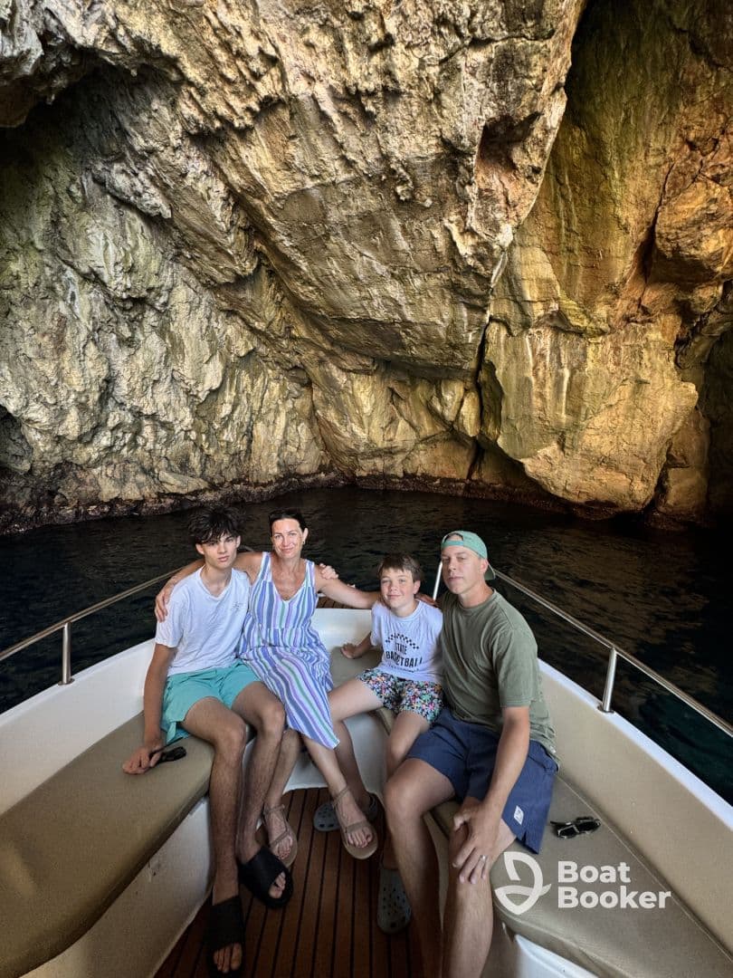 A family enjoys a moment aboard their boat inside a stunning cave, creating unforgettable memories during their adventure.