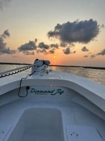 A serene view of the 'Diamond Jig' boat at sunset, showcasing its sleek design against a colorful sky — perfect for evening cruises in Avalon Manor, NJ.