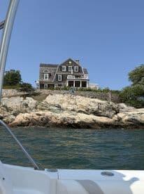 A picturesque view of a coastal house from a boat, showcasing the beautiful shoreline and rocky landscape — perfect for scenic boat tours.