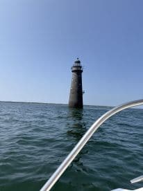 A picturesque view of a lighthouse standing tall over calm waters, perfect for capturing the beauty of a boating adventure.