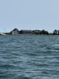 A picturesque view of a coastal building along the shoreline, showcasing the serene waters and inviting atmosphere — perfect for a relaxing day on the boat.