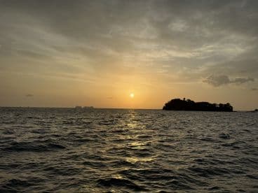 A breathtaking sunset over the ocean, with an island silhouette in the foreground — a perfect scene for romantic evenings or tranquil boat rides.