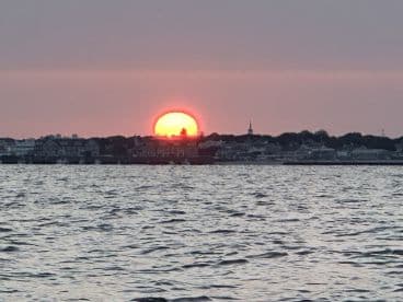 A stunning sunset casts a warm glow over the coastline, creating a picturesque backdrop perfect for evening boat cruises.