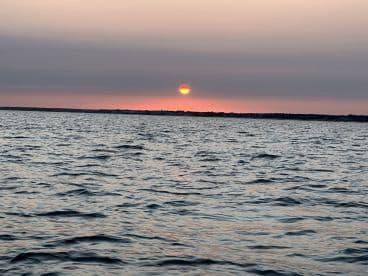 A serene sunset over calm waters, creating a picturesque backdrop perfect for evening boat cruises.
