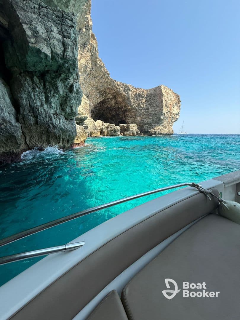 A stunning view of a rocky coastline with crystal-clear turquoise waters, showcasing the beauty of a boat trip through scenic landscapes.