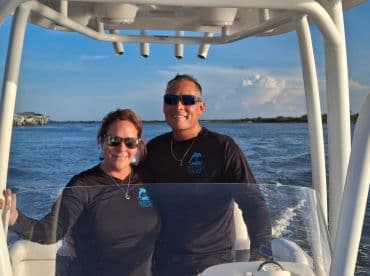 A couple enjoys a scenic boat ride, smiling together as they navigate the waters — perfect for romantic outings or adventure trips.