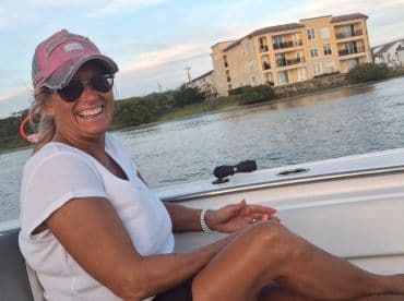 A joyful woman enjoys her time on a boat, showcasing the fun and relaxation of a day on the water.